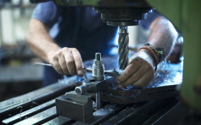 Worker operating industrial machine in metal workshop.