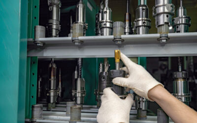 A worker inspects and selects a cutter from a rack to use on a CNC machine.